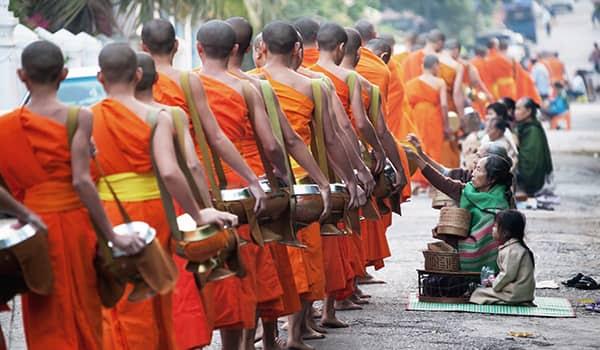 Monks in saffron robes collecting alms at dawn