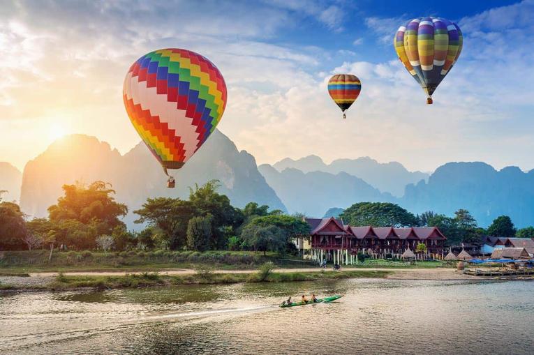 Hot air balloons flying over green karst mountains