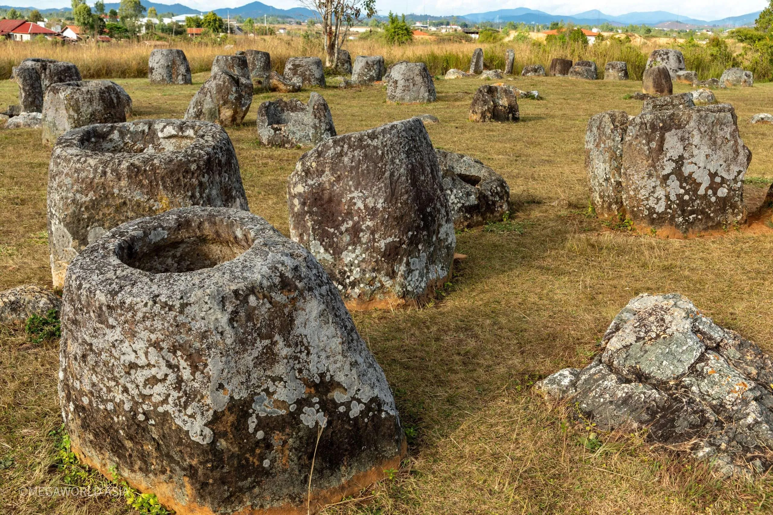 Large ancient stone jars scattered across a grassy plain